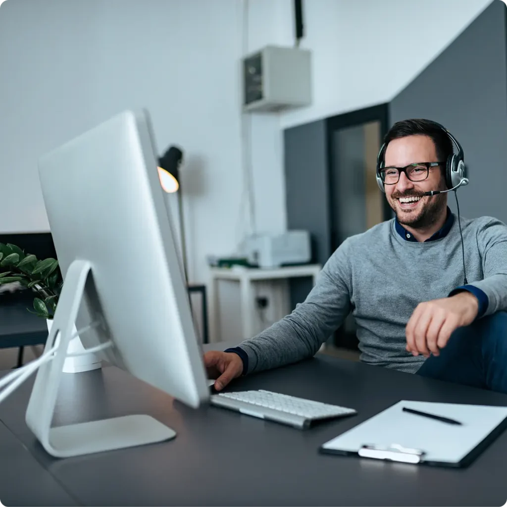 A man in headphones sits at a computer