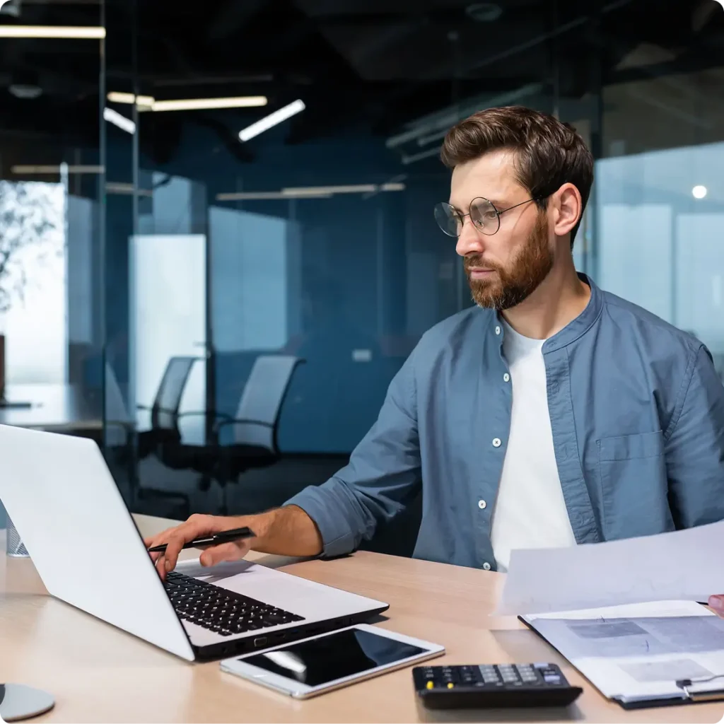 A man in a business suit is focused on his laptop